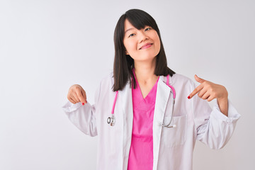 Young beautiful chinese doctor woman wearing stethoscope over isolated white background looking confident with smile on face, pointing oneself with fingers proud and happy.
