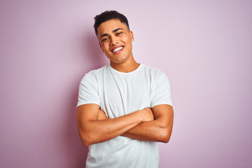 Young brazilian man wearing t-shirt standing over isolated pink background happy face smiling with...