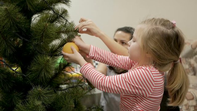 Happy family decorating a Christmas tree with boubles in the living-room