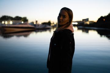 Blonde woman portrait standing by the river at night