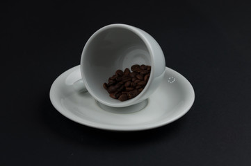 White cup of coffee and coffee beans isolated on black background