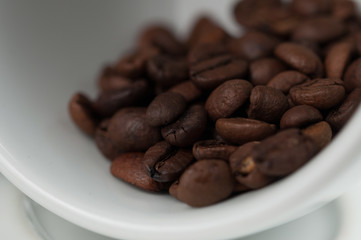 White cup of coffee and coffee beans isolated on black background