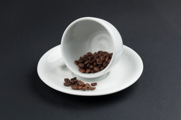 White cup of coffee and coffee beans isolated on black background