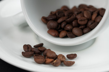 White cup of coffee and coffee beans isolated on black background