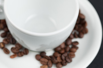 White cup of coffee and coffee beans isolated on black background