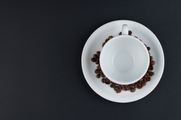 White cup of coffee and coffee beans isolated on black background