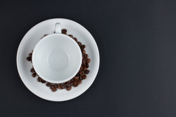 White cup of coffee and coffee beans isolated on black background