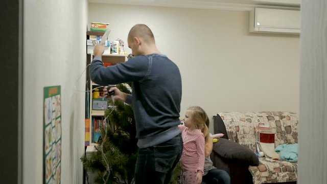 Happy family decorating a Christmas tree with boubles in the living-room