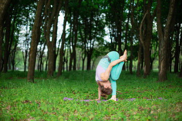 Thin brunette girl plays sports and performs beautiful and sophisticated yoga poses in a summer...