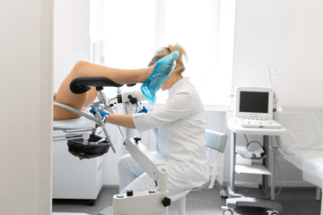 A gynecologist examines a patient on a gynecological chair. Workflow of a gynecologist - obrazy, fototapety, plakaty