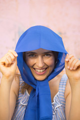 happy young woman with blue headscarf standing in front rusty metal background