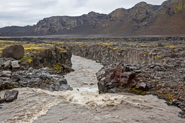 Stormy mountain river flows from glaciers in Iceland.