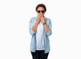 Beautiful young african american woman wearing sunglasses over isolated background shocked covering mouth with hands for mistake. Secret concept.