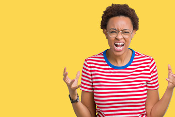 Beautiful young african american woman wearing glasses over isolated background crazy and mad...