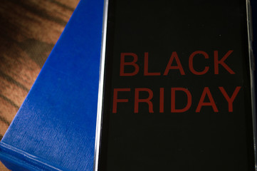 smartphone displaying generic application (app) with information BLACK FRIDAY in screen, on table with dramatic lighting