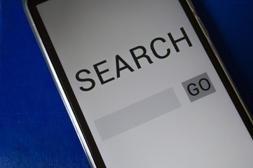 smartphone displaying generic application with search app in screen, on table with dramatic lighting