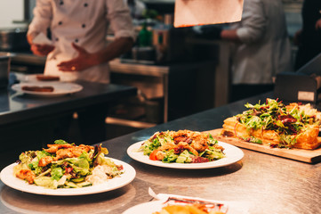 Food orders on the kitchen table in the restaurant, fresh green salad with fried chicken breast
