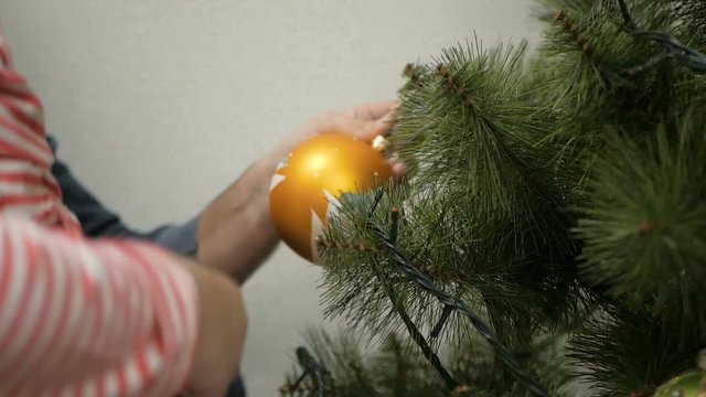 Happy family decorating a Christmas tree with boubles in the living-room