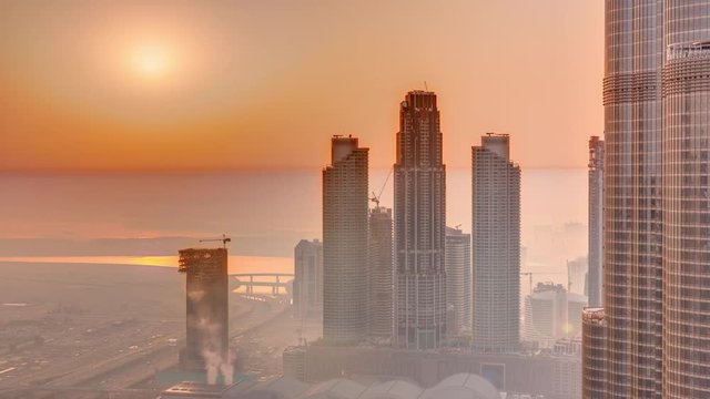 Amazing sunrise aerial view of Dubai downtown skyscrapers morning timelapse with haze, Dubai, United Arab Emirates. Modern towers and construction site