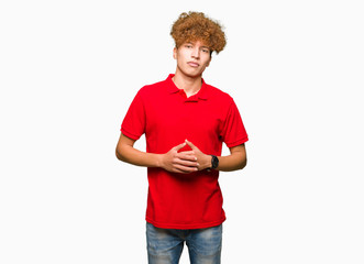 Young handsome man with afro hair wearing red t-shirt Hands together and fingers crossed smiling relaxed and cheerful. Success and optimistic