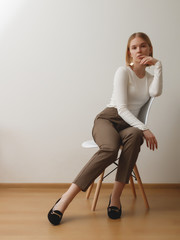 Fashionable girl in a white sweater and checkered pants . Natural lifestyle portrait of girl , emotional and fashion mood ,chic clothes and summer theme . Soft warm vintage color tone . Gold earrings