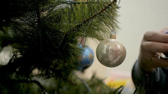 Happy family decorating a Christmas tree with boubles in the living-room