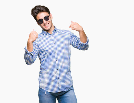 Young handsome man wearing sunglasses over isolated background looking confident with smile on face, pointing oneself with fingers proud and happy.