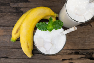 Banana smoothie white fruit juice milkshake blend beverage healthy high protein the taste yummy In glass,drink episode morning on a wooden background  from top view.