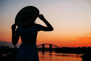 Woman standing in the river bank in the sunset
