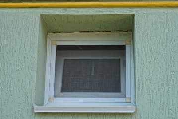 one small white square window on the gray wall of the house