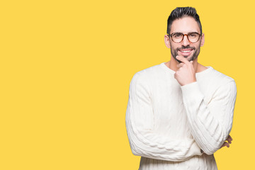 Young handsome man wearing glasses over isolated background looking confident at the camera with smile with crossed arms and hand raised on chin. Thinking positive.