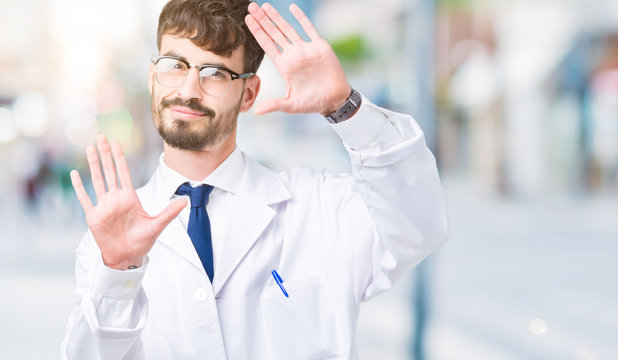 Young professional scientist man wearing white coat over isolated background Smiling doing frame using hands palms and fingers, camera perspective