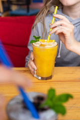 Young woman is drinking fresh pulpy orange juice with ice