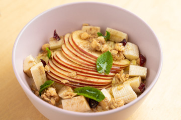 Close up of oatmeal with sliced apple, nuts, honey and cinnamon on wooden table