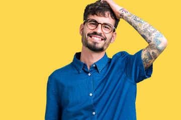 Young handsome man wearing glasses over isolated background Smiling confident touching hair with hand up gesture, posing attractive