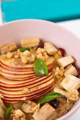 Close up of oatmeal with sliced apple, nuts, honey and cinnamon on wooden table