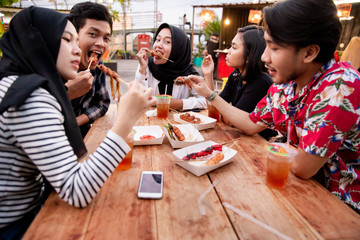 Group of young friends enjoying meal in outdoor cafe on the building rooftop