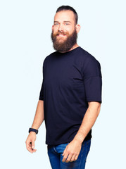 Fototapeta premium Young blond man wearing casual t-shirt looking away to side with smile on face, natural expression. Laughing confident.