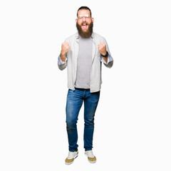 Fototapeta premium Young blond man wearing glasses very happy and excited doing winner gesture with arms raised, smiling and screaming for success. Celebration concept.