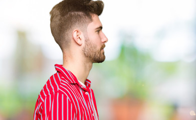 Young handsome man wearing red shirt looking to side, relax profile pose with natural face with confident smile.