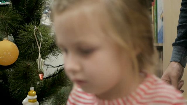 Happy family decorating a Christmas tree with boubles in the living-room
