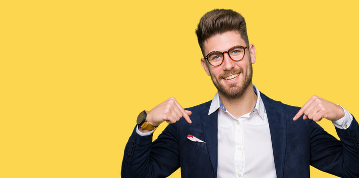 Young handsome business man wearing glasses looking confident with smile on face, pointing oneself with fingers proud and happy.