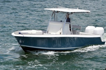 Fototapeta premium Small open blue and white fishing boat with white fiberglass canopy powered by two outboard engines