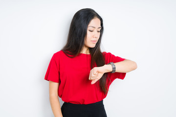 Beautiful brunette woman wearing red t-shirt over isolated background Checking the time on wrist watch, relaxed and confident