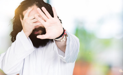 Man wearing Jesus Christ costume covering eyes with hands and doing stop gesture with sad and fear expression. Embarrassed and negative concept.