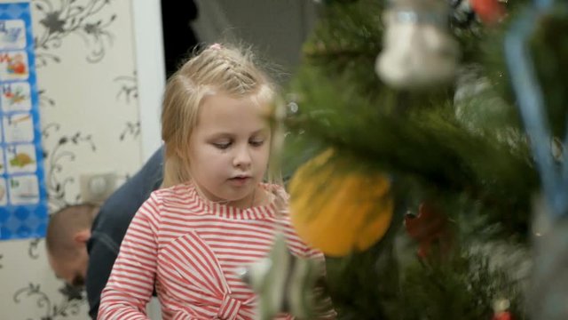 Happy family decorating a Christmas tree with boubles in the living-room