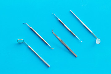 Dentist work desk with tools for teeth on blue background top view