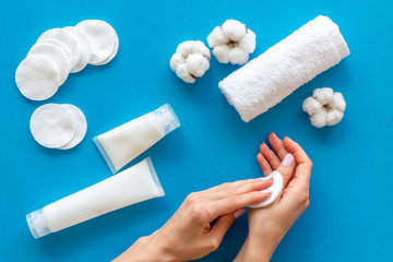 pattern of cosmetic cotton pads and cream, cream on blue background top view