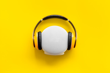 Wireless speaker and headphones as music gadgets on yellow background top view