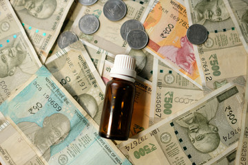 Empty Medicine bottle on Indian currency notes. Isolated focus. Medicine bill concept 